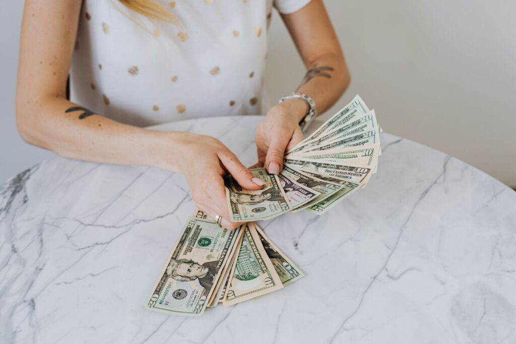 Close-up of a person counting US dollar bills on a luxurious marble table, symbolizing wealth and fi