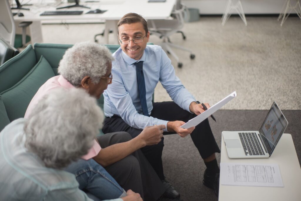 Consultant discussing financial plans with senior clients in a modern office setting, using document